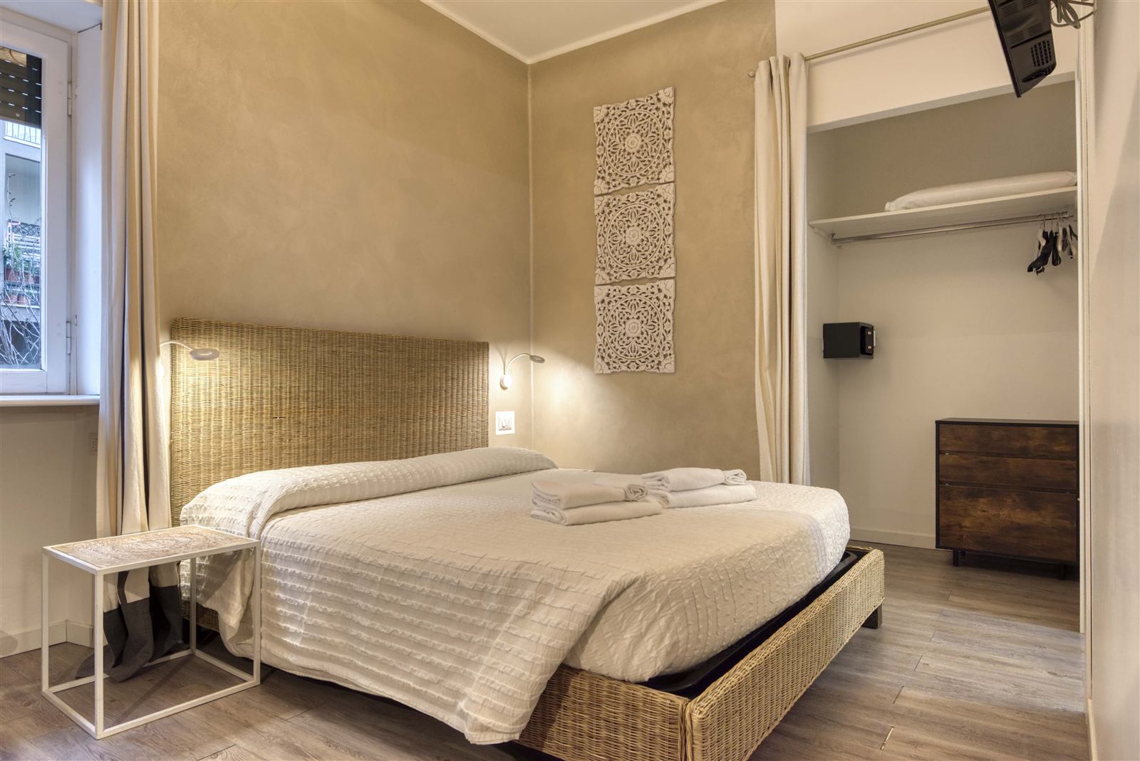 Camera di Maison Castelli in centro a Bergamo, letto in vimini e toni caldi